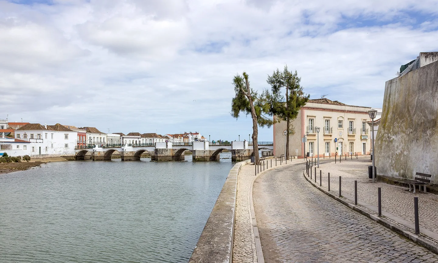 De rivieroever van Tavira met gepleisterde huizen en palmbomen langs het water